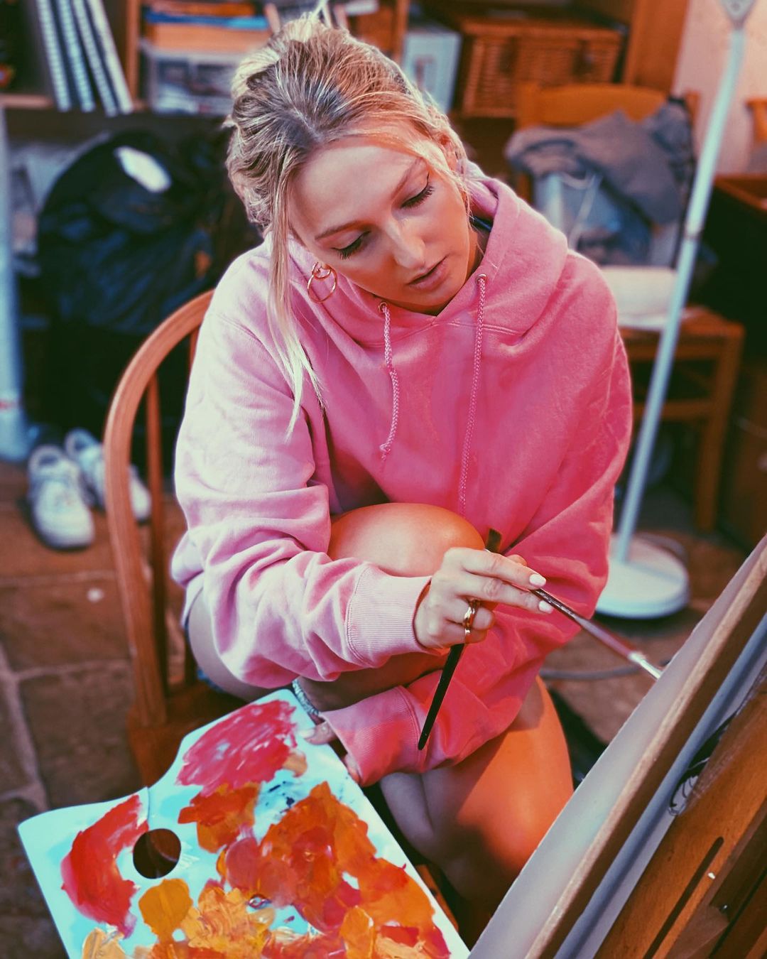 Georgia Hirst loves to paint and Sketch her days away. She is wearing a pink jumper and using a brush on a canvas