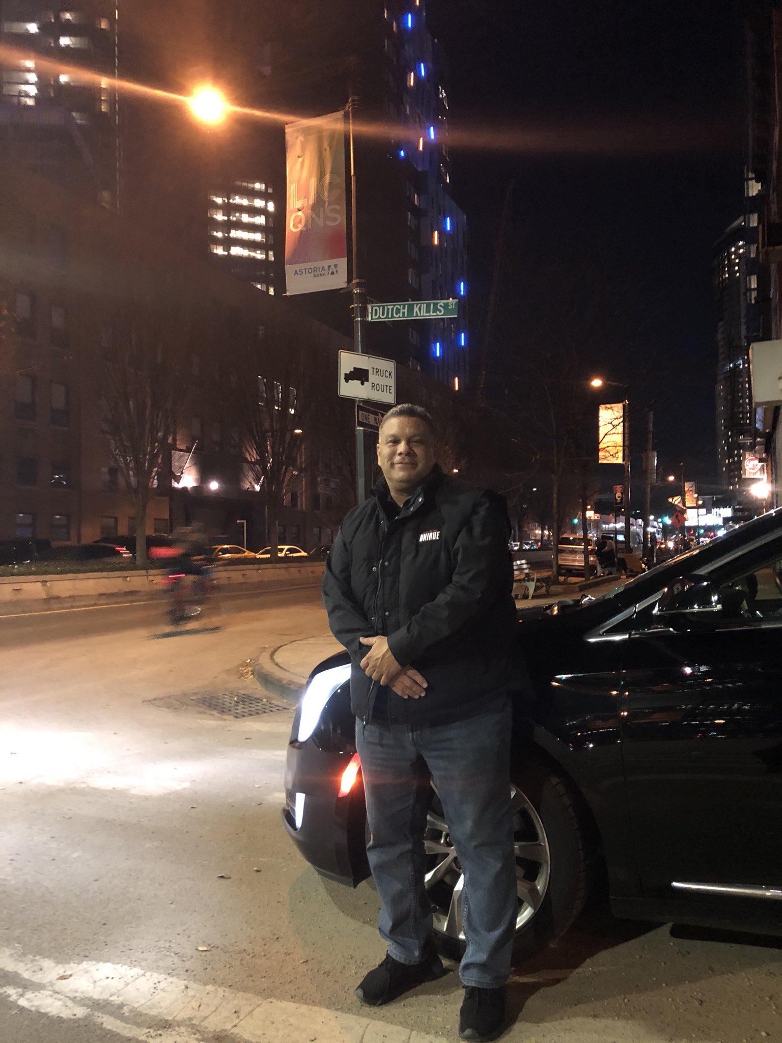 Will Castro Striking a pose in a black jackey leaning in front of a car