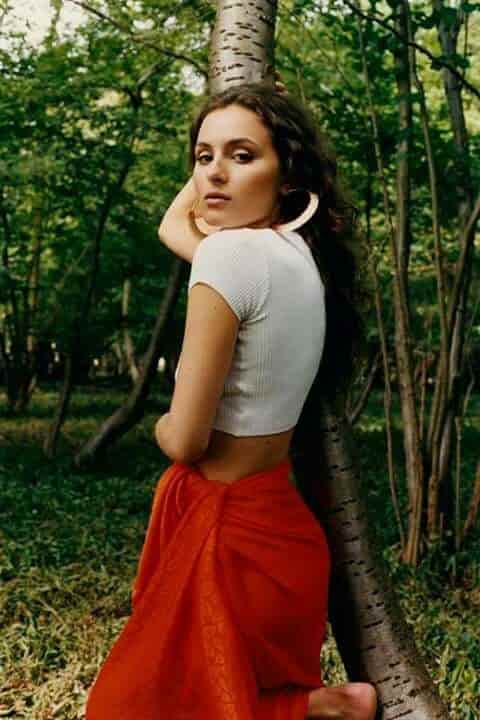 Lily Sastry posing in white top and red skirt.