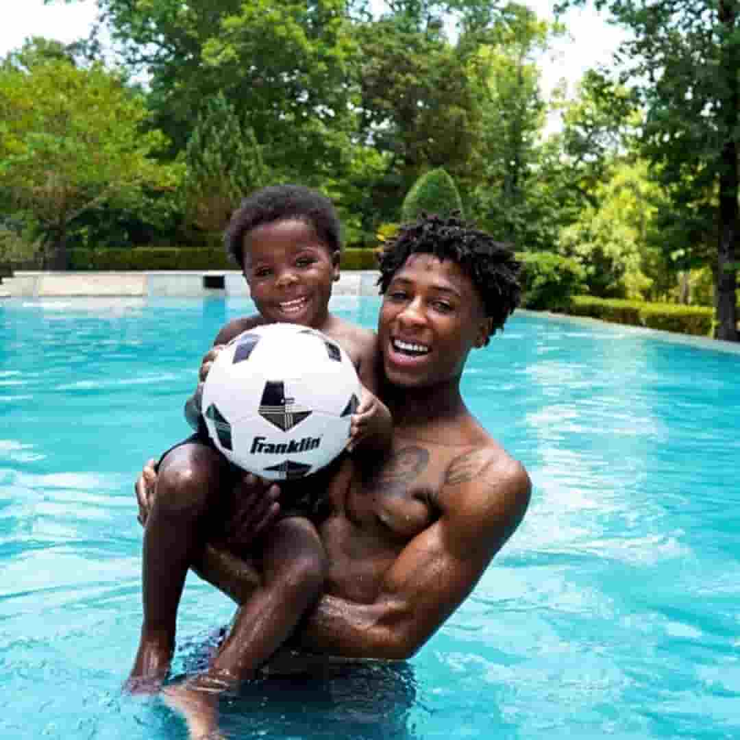 Kamiri Gaulden with his father YoungBoy Never Broke Again (Kentrell DeSean Gaulden) in swimming pool holding a football.